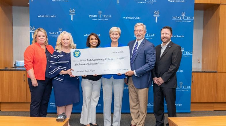 Diana Urieta holds up a giant check with members of the Wake Tech Community College Board of Trustees